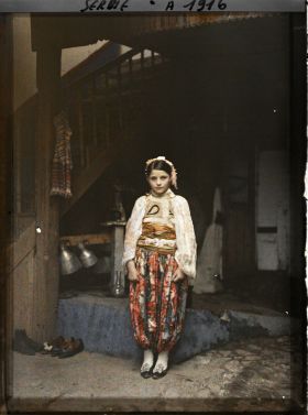 Image représentant Une fillette serbe en costume traditionnel dans la cour d'une maison