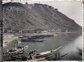 Image représentant Au pied de la forteresse Rozafa, barques pirogues amarrées à une berge de la Buna, longée par une voie de charriots