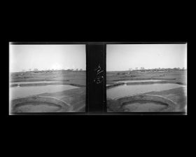 Image représentant Des bassins de pisciculture aux abords d'un village, vue prise du train