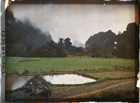 Image représentant Des rizière au pied des rochers, à gauche au premier plan, un tombeau Mnong