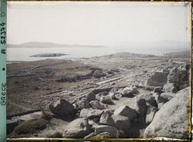 Image représentant Panorama vers les ruines de la ville antique (haute et basse) et la mer, depuis l'antre du Cynthe sur le versant occidental du mont Cynthe (au fond, l'Ile de Syros)