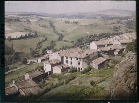 Image représentant Le Rocher de Saint Flour au premier plan et les maisons à toits plats de la rue descendante