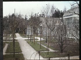 Image représentant Partie est du verger-roseraie en début de printemps, traversée par une allée menant à la forêt bleue