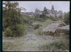 Image représentant La ville haute vue de la rive droite avec les meules de paille de l'usine au premier plan