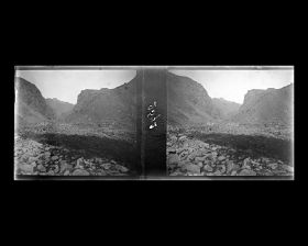 Image représentant Le lit du torrent encombré par de grosses pierres et le paysage montagneux