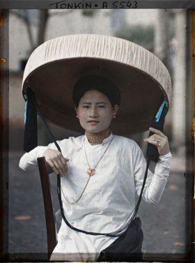 Image représentant Une jeune femme quarteronne portant le grand chapeau en feuilles de latanier muni d'une longue jugulaire ornée de pompons