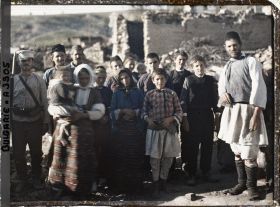 Image représentant Groupe d'hommes, de femmes et d'enfants et un soldat au milieu de décombres du village