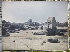 Image représentant L'oratoire de Saint-Guirec à marée basse ; à l'arrière-plan, le château de Costaéres