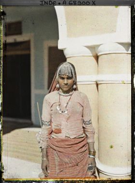 Image représentant Portrait en plan américain d'une femme à l'entrée d'une maison ou dans une cour intérieure