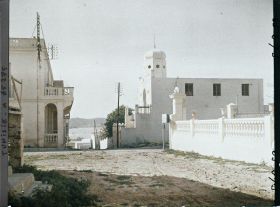 Image représentant Une rue avec à droite la synagogue et la mer à l'arrière-plan