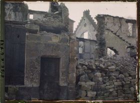 Image représentant En face du magasin Ygouf, ruines avec une porte peinte brûlée, au 1er plan