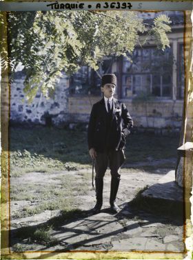 Image représentant Portrait d'un homme, "docteur Namik Adil" d'après le registre des légendes ; il porte des vêtements occidentaux (cravate, veste de costume avec pochette, pantalon d'équitation, bottes) et un chapeau traditionnel ; il tient un fouet à la main