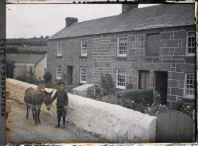 Image représentant Un enfant et un âne près d'une maison