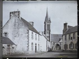 Image représentant Une place du village et l'église Saint-Jean-du-Doigt derrière la porte monumentale du cimetière