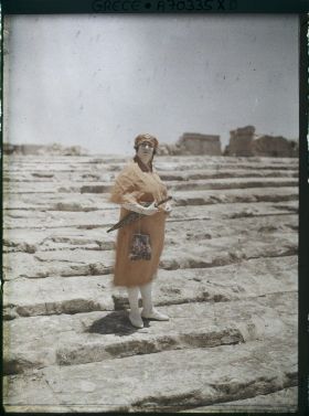 Image représentant Femme d'une quarantaine d'années élégamment vêtue, sur les marches d'un site archéologique (guide, interprète, compagne de l'opérateur ?)