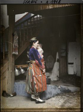 Image représentant Une Serbe en costume traditionnel dans la cour d'une maison