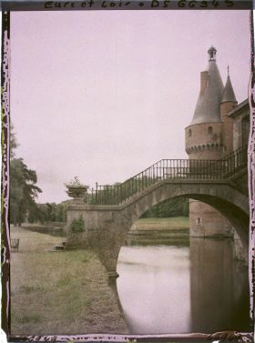 Image représentant Le pont de pierre au-dessus des douves du château et la tour de brique avec toiture en poivrière