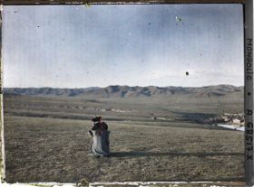 Image représentant Une femme khalkha, assise de dos, contemple la montagne située au nord d'Ourga