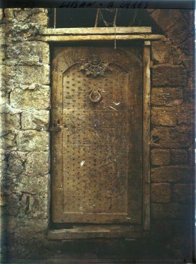 Image représentant Porte ancienne de bois clouté dans une cour d'église