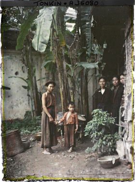 Image représentant Des femmes et un enfant dans un coin de cour planté de bananiers