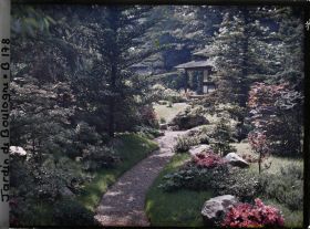 Image représentant Étroit chemin ombragé, orné de pierres et d'azalées, menant à la maison ouest du " village japonais "