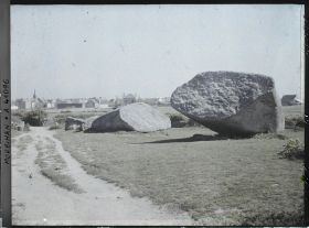 Image représentant Le Grand Menhir brisé ; à l'arrière-plan, le village de Locmariaquer