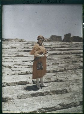 Image représentant Femme d'une quarantaine d'années élégamment vêtue, sur les marches d'un site archéologique (guide, interprète, compagne de l'opérateur ?)