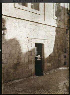 Image représentant Une religieuse coiffée de sa cornette devant la porte de la cinquième station sur la Via Dolorosa