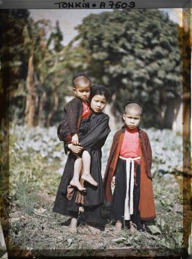 Image représentant Une jeune fille en turban tenant par la main deux enfants de moins de douze ans