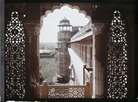 Image représentant Tour extérieure surmontée d'un chhatri, vue d'une fenêtre encadrée de jalis (dentelle de pierre formant claustra) dans le fort Rouge (Lal Qila)