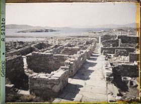 Image représentant La rue du Théâtre, vue vers la ville basse. Au fond, l'ile de Tinos