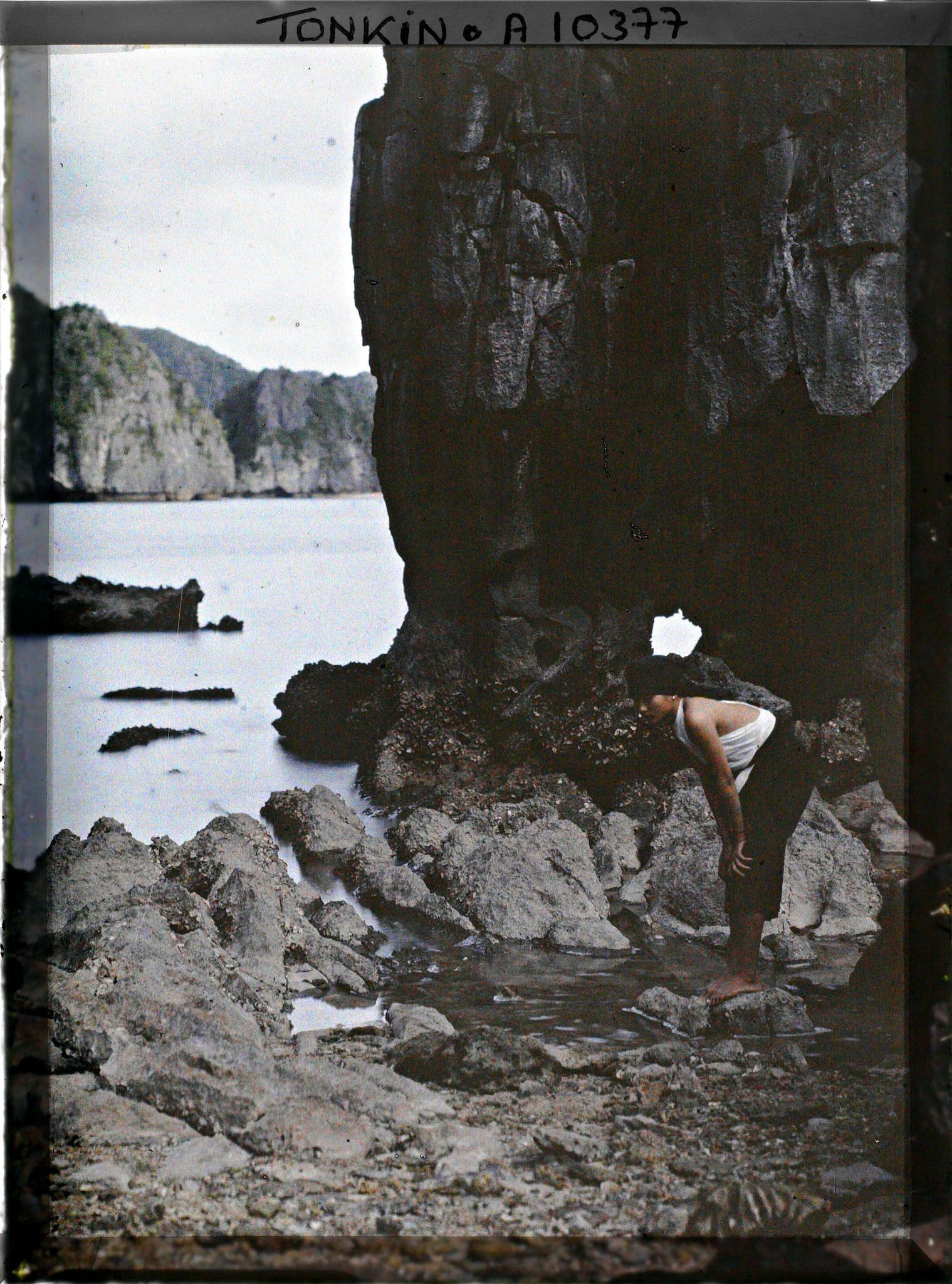 Image représentant Une jeune fille penchée au bord de l'eau, dans les rochers près du Tunnel de Cam-pha (ou " Tunnel de la Douane ")