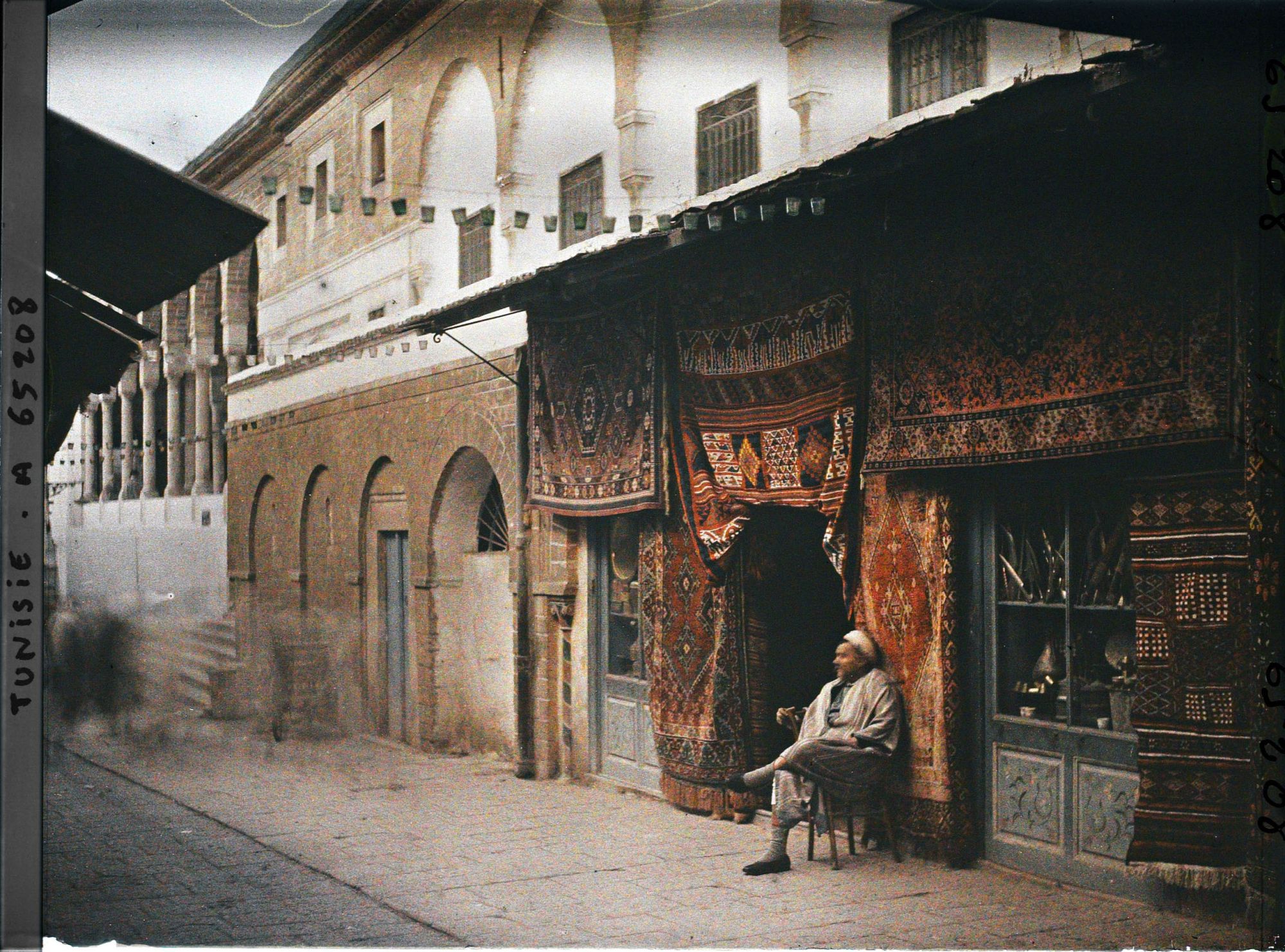 Image représentant Un marchand de tapis, d'armes blanches et d'antiquité dans le Souk Djamaa ez Zitouna, au pied de la façade de la Grande mosquée