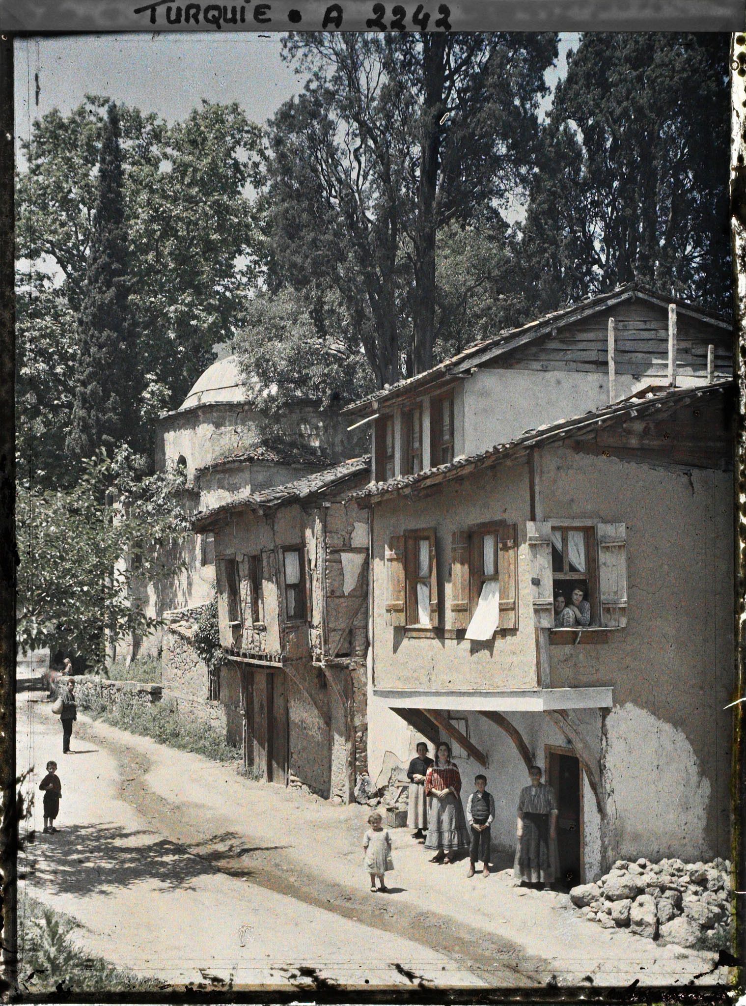 Image représentant Femmes et enfants devant et à la fenêtre d'une maison dans une rue de terre battue