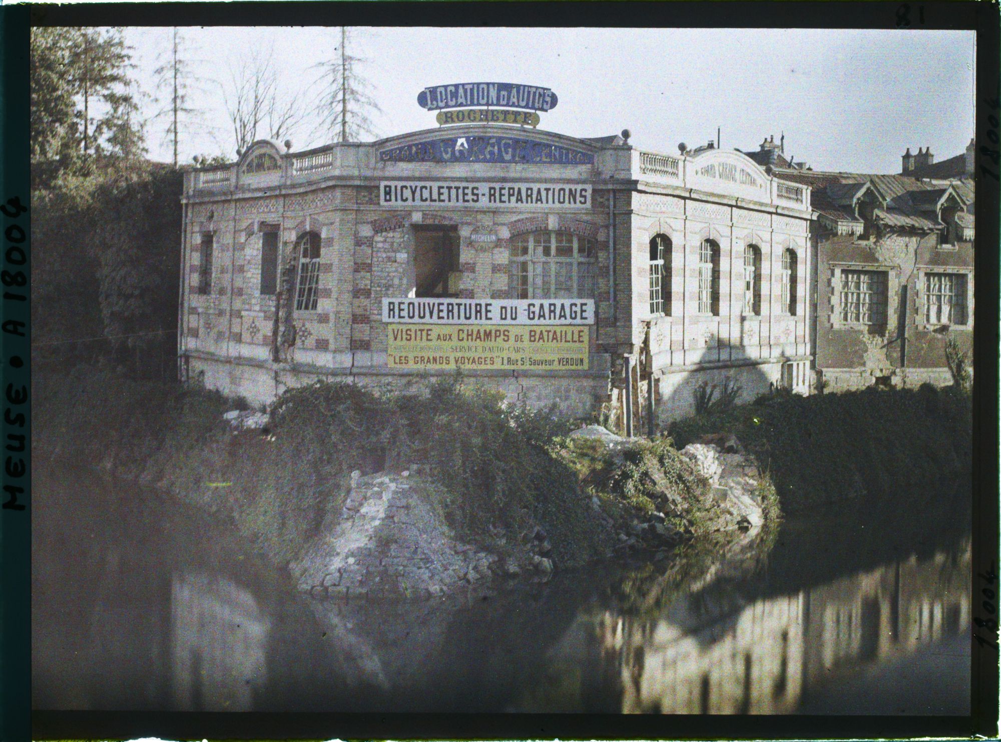 Image représentant France, Verdun, Un garage d'automobiles s/ les bords de la Meuse : On lit l'affiche des Voyges s/ le front.