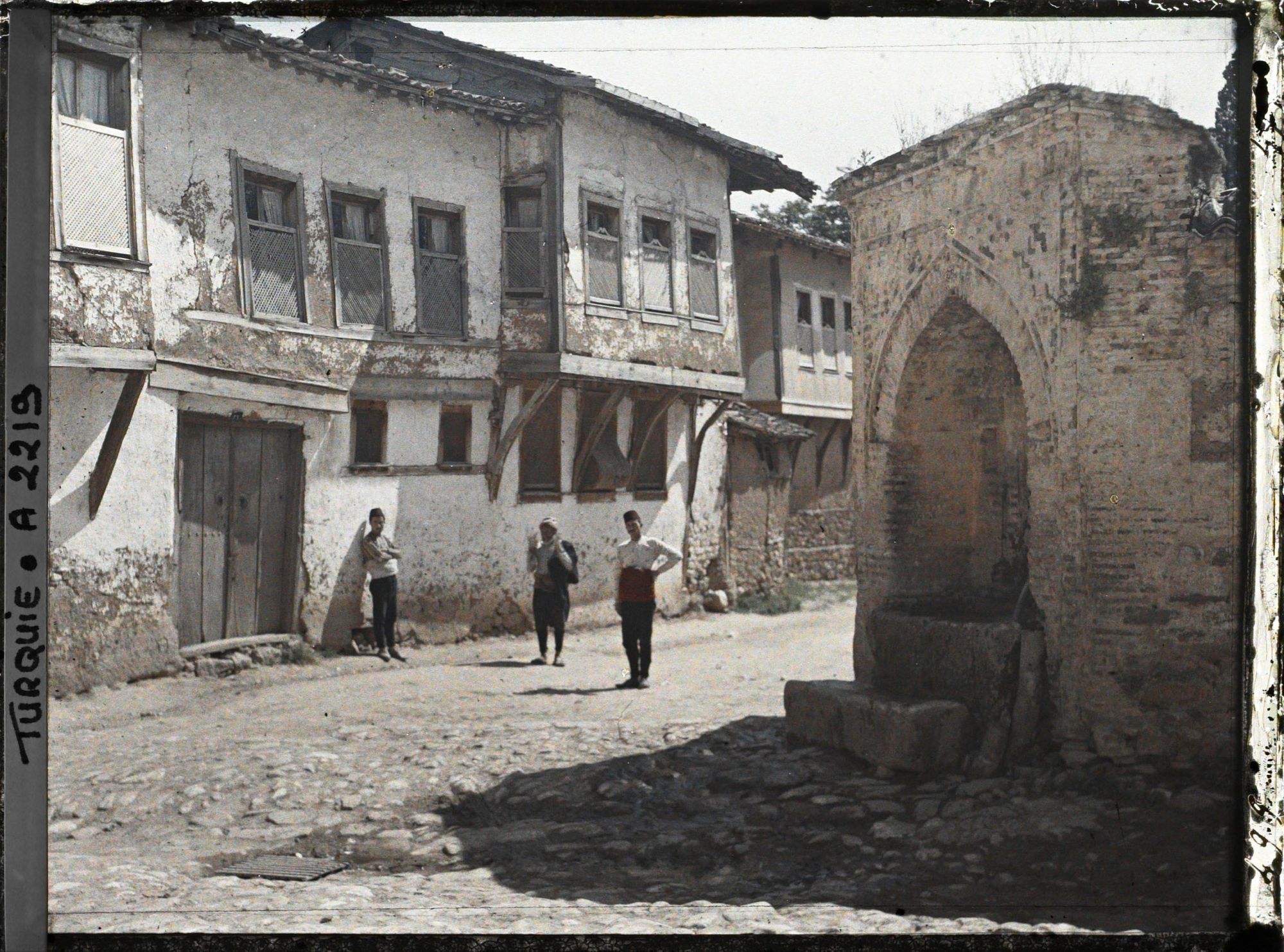 Image représentant Trois hommes devant des maisons modestes
